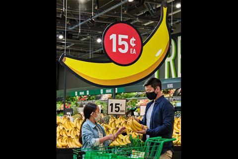 People stand in front of a display of bananas in the Amazon Fresh store